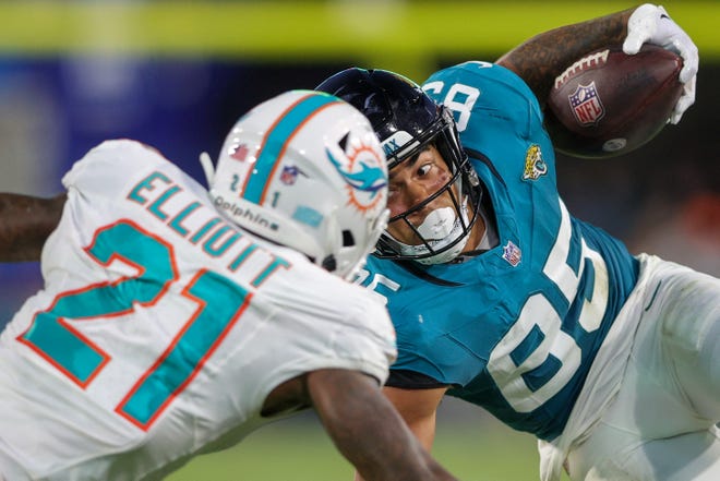 Aug. 26: Jacksonville Jaguars tight end Brenton Strange (85) stretches for extra yards while defended by Miami Dolphins safety DeShon Elliott.
