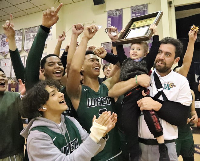 Weed High School players celebrate as Robert West Jr., the 3-year-old son of head coach Robert West, right, holds their Northern Section Division 6 championship plaque. Weed edged Redding Christion 45-42 for the title on Friday, Feb. 25, 2022, in Palo Cedro.