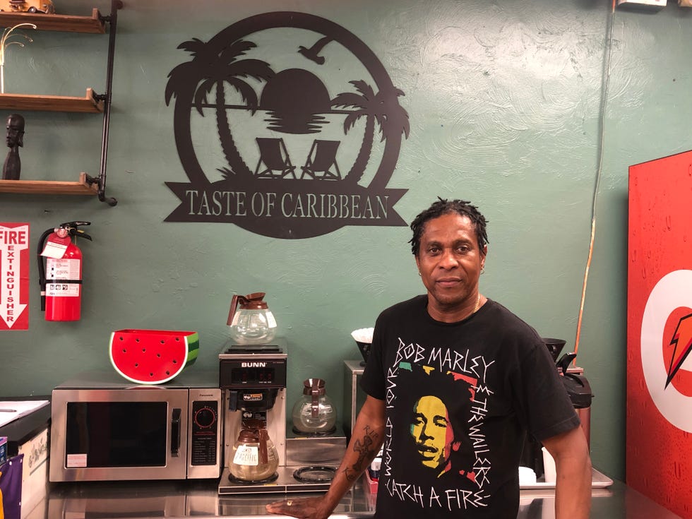 Taste of Caribbean owner Kevin Sampson stands in front of a coffee maker and microwave on Sunday, July 9, 2022.